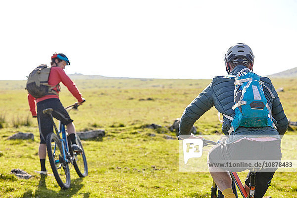 Rear view of cyclists cycling on hillside
