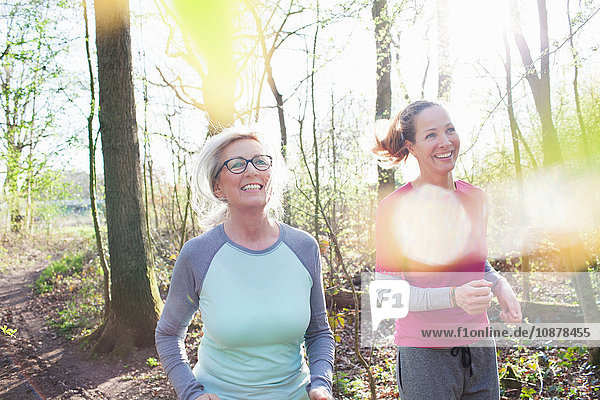 Frauen joggen lächelnd im Wald