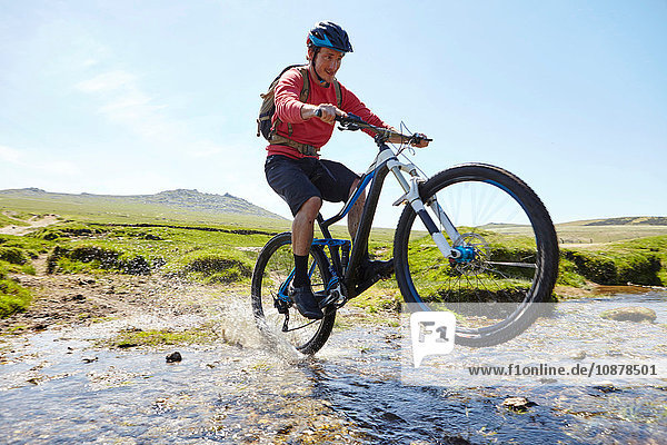 Cyclist doing wheelie through water
