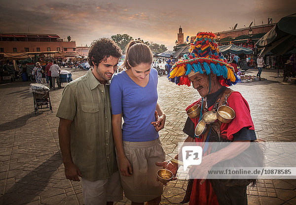 Junges Paar im Gespräch mit einem Markthändler  Jemaa el-Fnaa-Platz  Marrakesch  Marokko