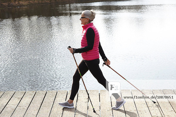 Seitenansicht der Nordic-Walking-Frau am Teich in voller Länge