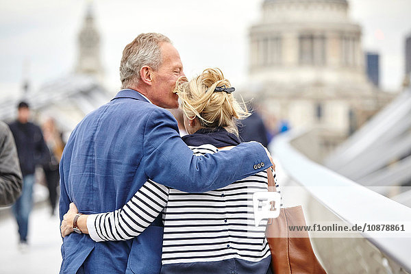 Rückansicht eines romantischen reifen Liebespaares beim Überqueren der Millennium Bridge  London  UK