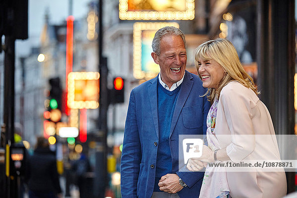 Mature dating couple giggling on city street at dusk  London  UK