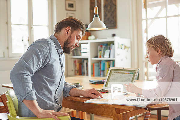Father helping son with homework in home office