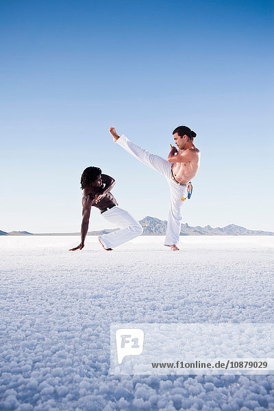 Two men opposite each other performing capoeira on Bonneville Salt Flats  Utah  USA
