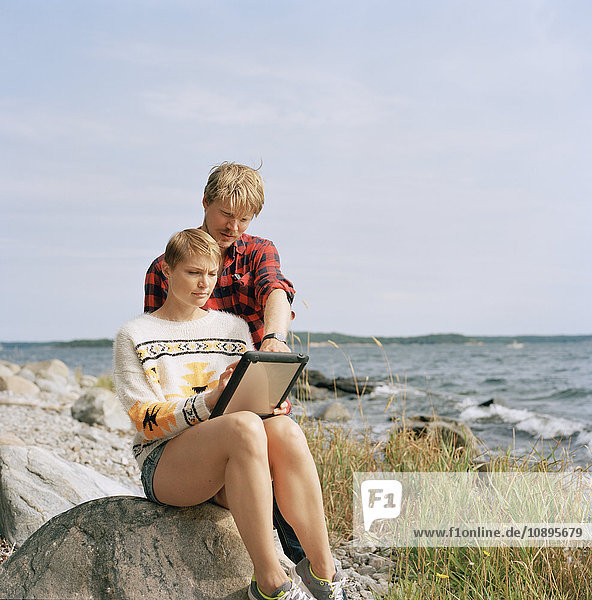 Schweden  Sodermanland  Galo  Paar mit Tablet PC am Strand