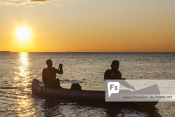 Schweden  Medelpad  Sundsvall  Essvik  Brattberget  Zwei Männer im Kanu bei Sonnenuntergang