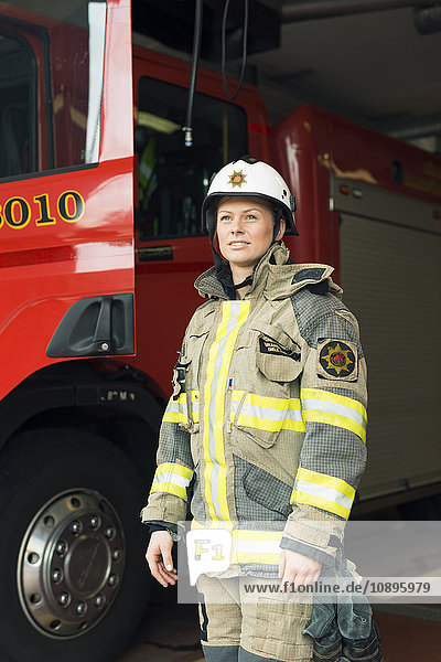 Schweden Lächelnde Feuerwehrfrau mit Löschfahrzeug