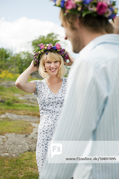 Junger Mann und Frau mit Blumenkränzen auf dem Kopf