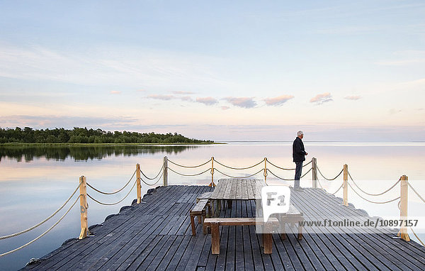 Schweden  Gotland  Lergrav  Mann auf Holzdeck stehend und auf das Meer blickend
