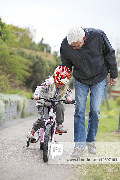 Sweden  Bohuslan  Tjorn  Man teaching granddaughter (4-5) to ride bicycle