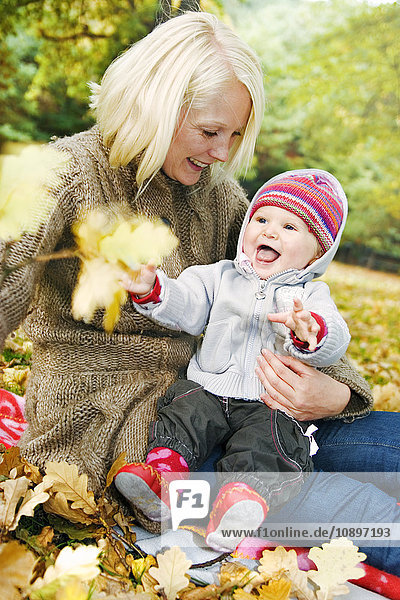 Schweden  Vastra Gotaland  Göteborg  Mutter sitzend mit Tochter (2-3) im Park im Herbst
