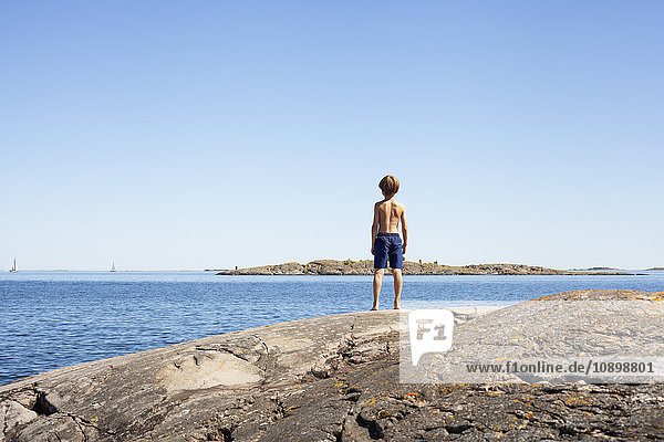 Schweden Uppland Runmaro Barrskar Rückansicht des Jungen (6-7) beim Blick aufs Meer