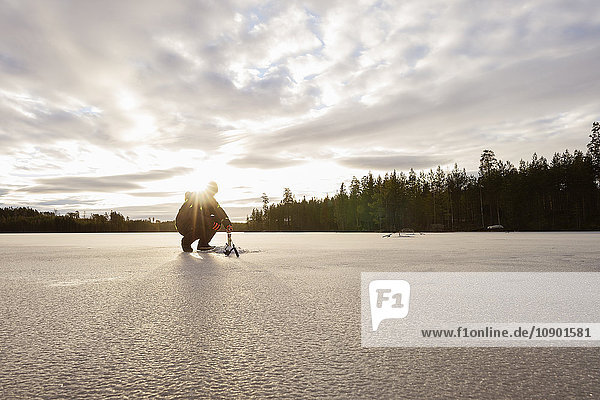 Schweden Vastmanland Bergslagen Hallefors Natsjon Mann der sich auf das Eisangeln auf dem zugefrorenen See vorbereitet.