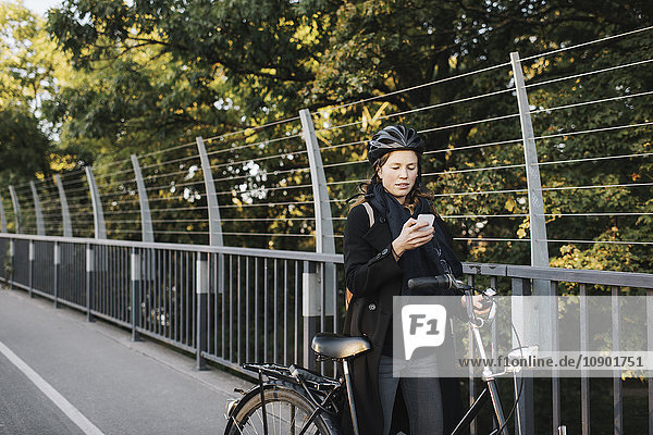 Schweden Sodermanland Stockholm Vasterbron Junge Frau auf dem Fahrrad mit dem Telefon