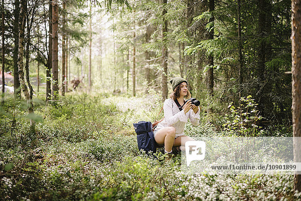 Schweden, Vasterbotten, Norrmjole, Junge Frau beim Fotografieren im Wald