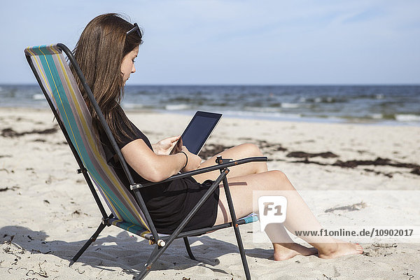 Schweden Skane Ahus Teenage girl (16-17) mit digitalem Tablett am Strand