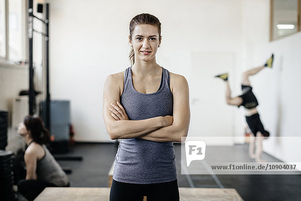 Deutschland Portrait einer jungen Frau im Fitnessstudio mit gekreuzten Armen
