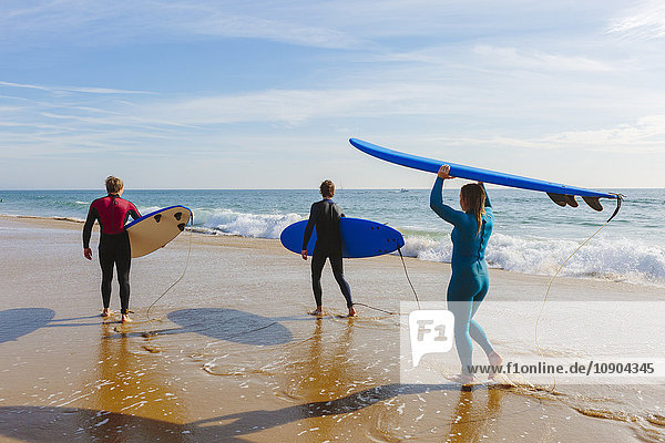 Portugal Lissabon Drei Personen mit Surfbrettern am Strand