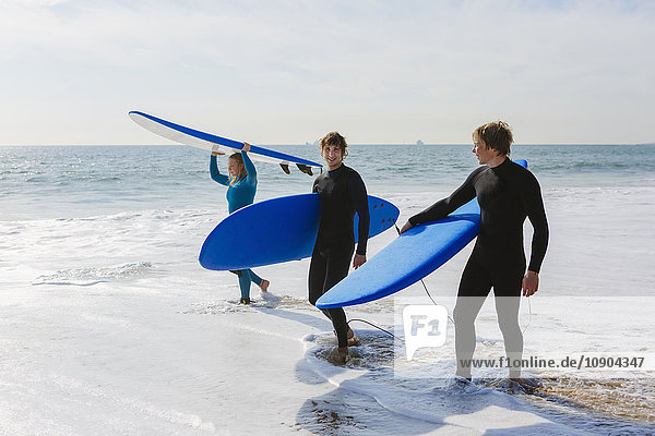 Portugal Lissabon Drei Personen mit Surfbrettern am Strand