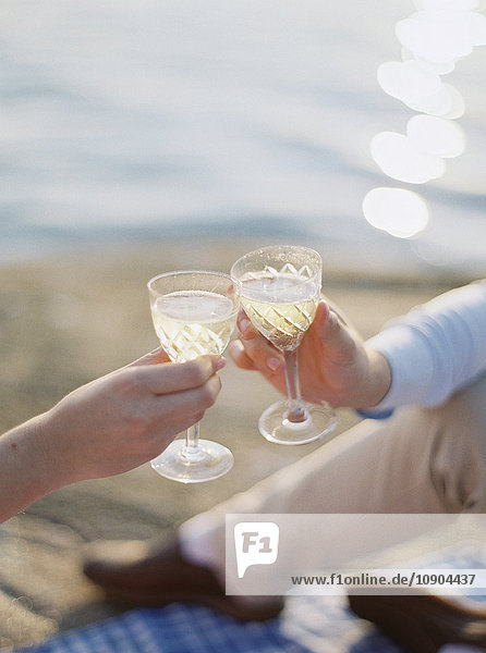 Schweden  Bohuslan  Fjallbacka  Paartoast mit Gläsern Champagner am Sandstrand