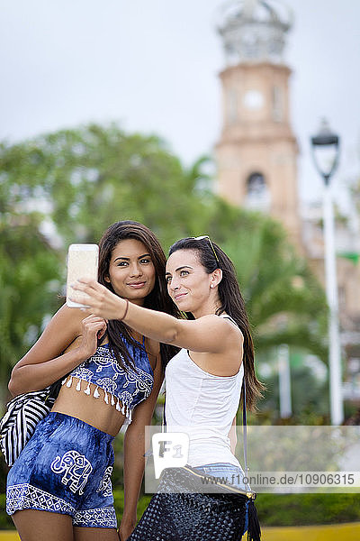 Mexico  Puerto Vallarta  two young women taking a smartphone selfie in the city
