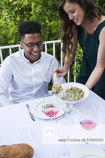 Woman serving tabbouleh to her guest during a summer dinner