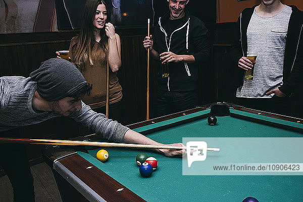 Man playing pool billard with friends in a bar