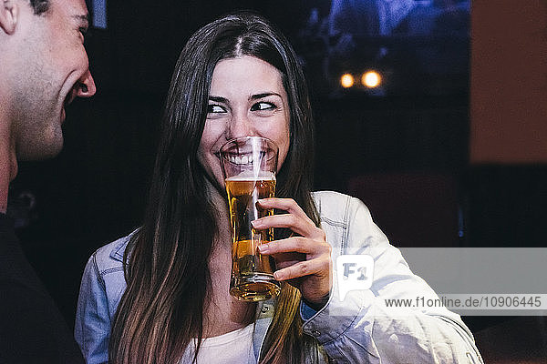 Smiling woman drinking a glass of beer with a man in a bar
