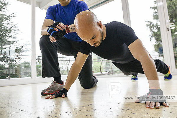 Man doing pushups while his trainer timing with his watch