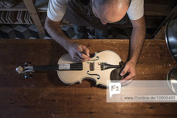 Luthier adjusting the sound post of an unvarnished violin in his workshop