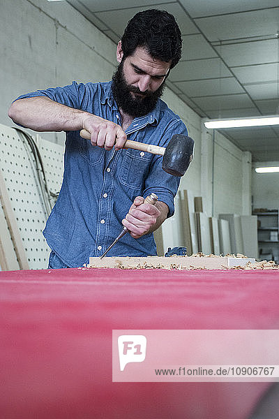 Carpenter using a chisel and hammer