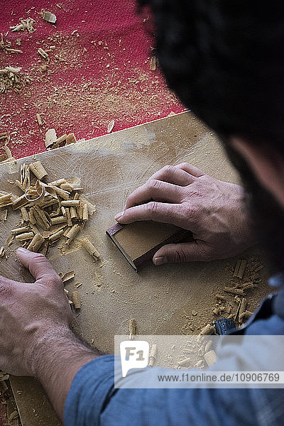 Hands of carpenter sanding a wood plank