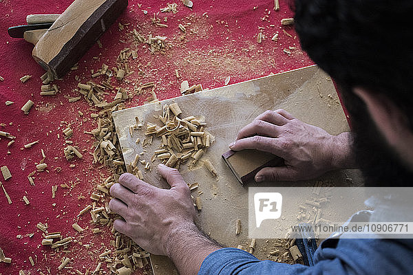 Hands of carpenter sanding a wood plank