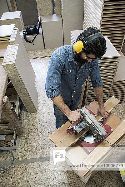 Carpenter with hearing protection and safety glasses using a circular saw