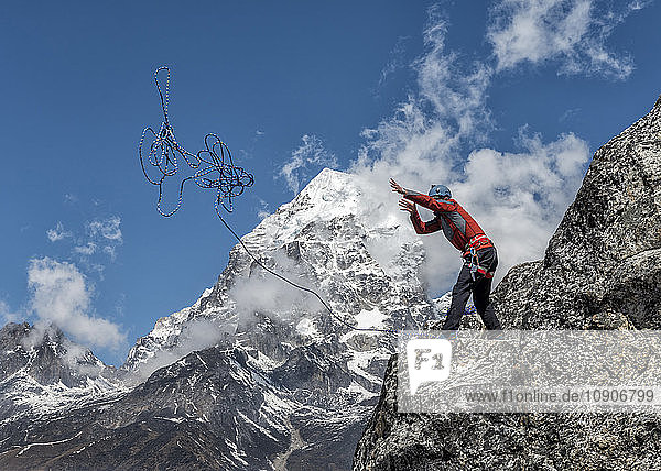 Nepal  Himalaya  Solo Khumbu  Ama Dablam  man standing on rock throwing rope