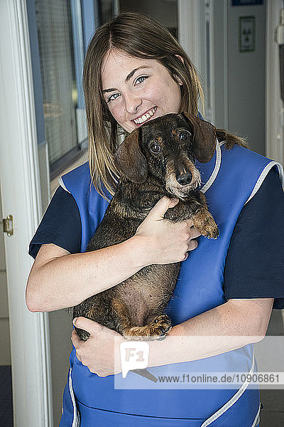 Portrait of smiling veterinarian holding dog in her arms