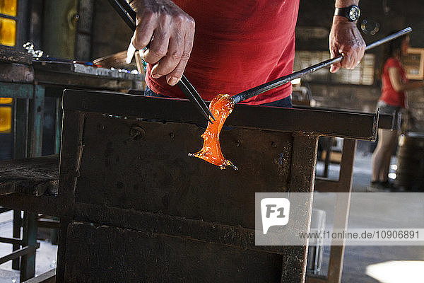 Man working with molten glass using a tweezers in a glass factory