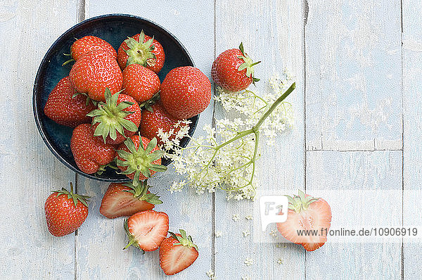 Bowl of strawberries and elderflower on wood