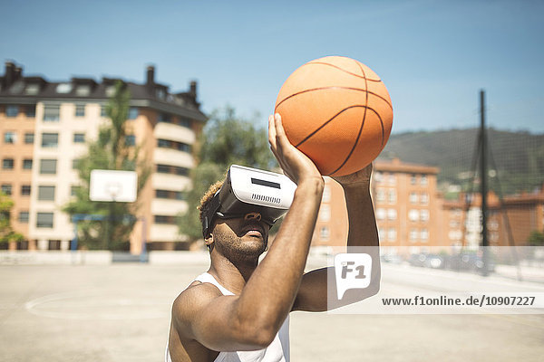 Junger Mann spielt Basketball mit Virtual-Reality-Brille auf
