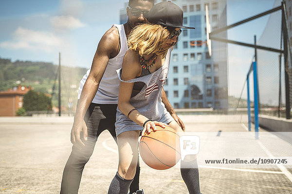 Junges Paar spielt Basketball auf dem Platz