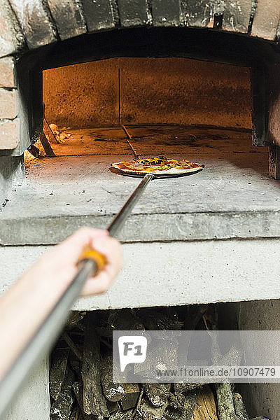Putting pizza in traditional oven