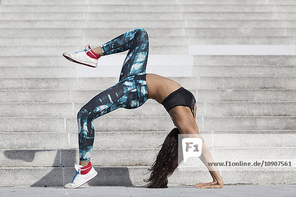 Young woman doing gymnastics at outdoor stairs
