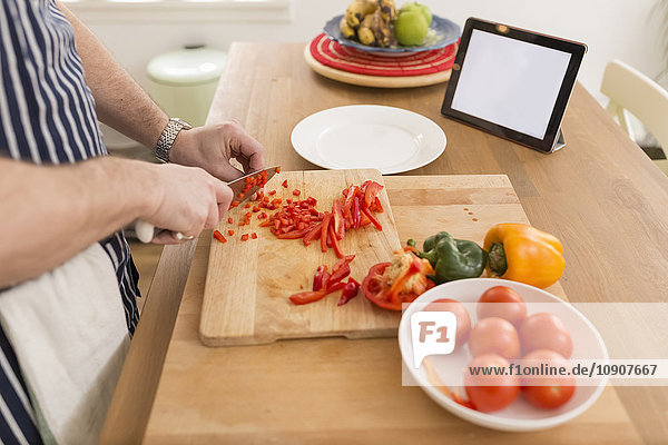 Man's hands dicing bell pepper on wooden board