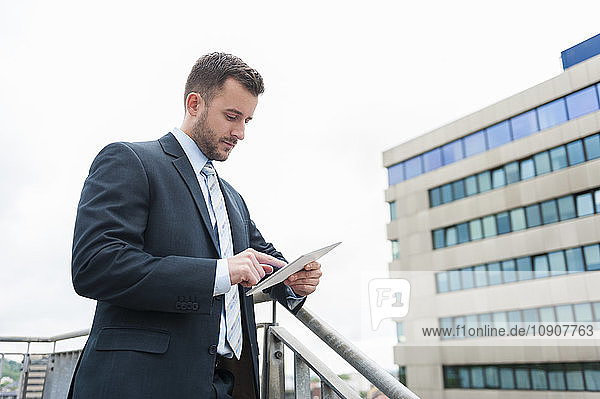 Businessman looking at digital tablet in front of office building
