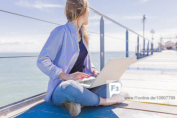 Woman using laptop on jetty