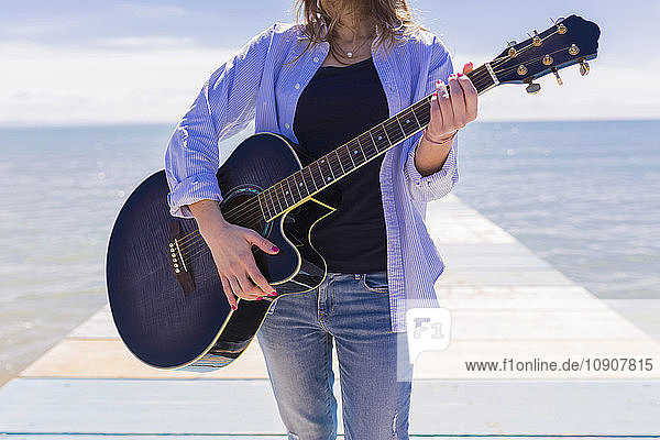 Young woman with guitar on jetty