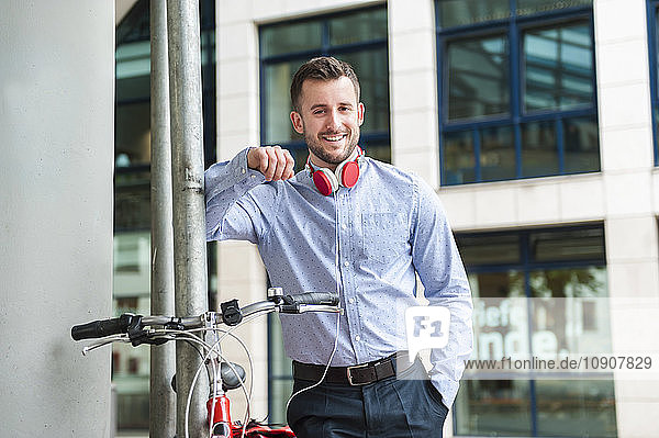 Portrait of smiling young man wearing headphones outdoors