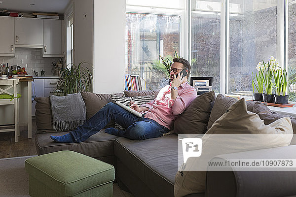 Mature man sitting on couch talking on the phone