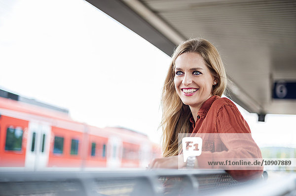 Porträt einer lächelnden jungen Frau auf dem Bahnsteig